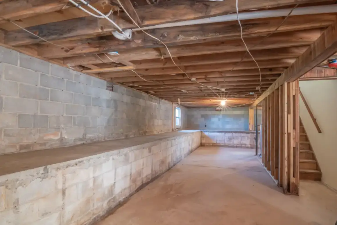 Basement block wall and exposed joists showing services needing access before boarding