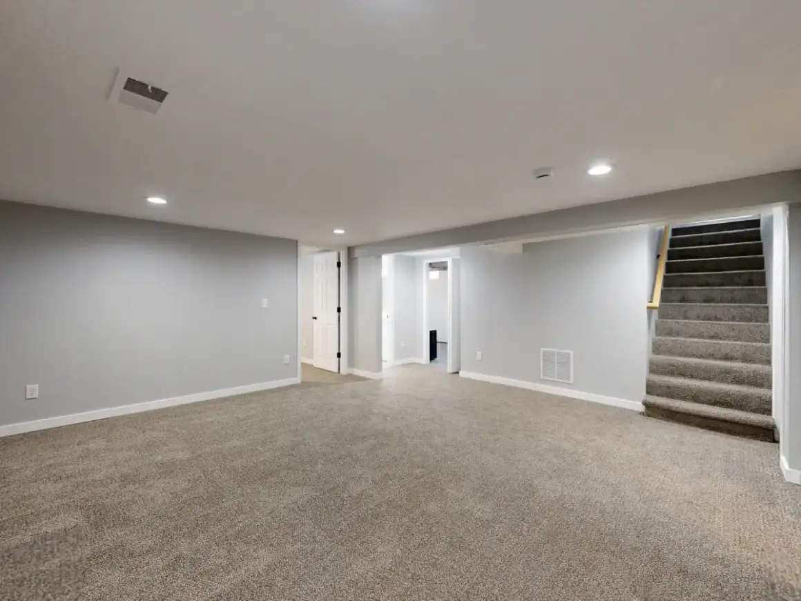 Finished basement room with boarded and painted walls and ceiling
