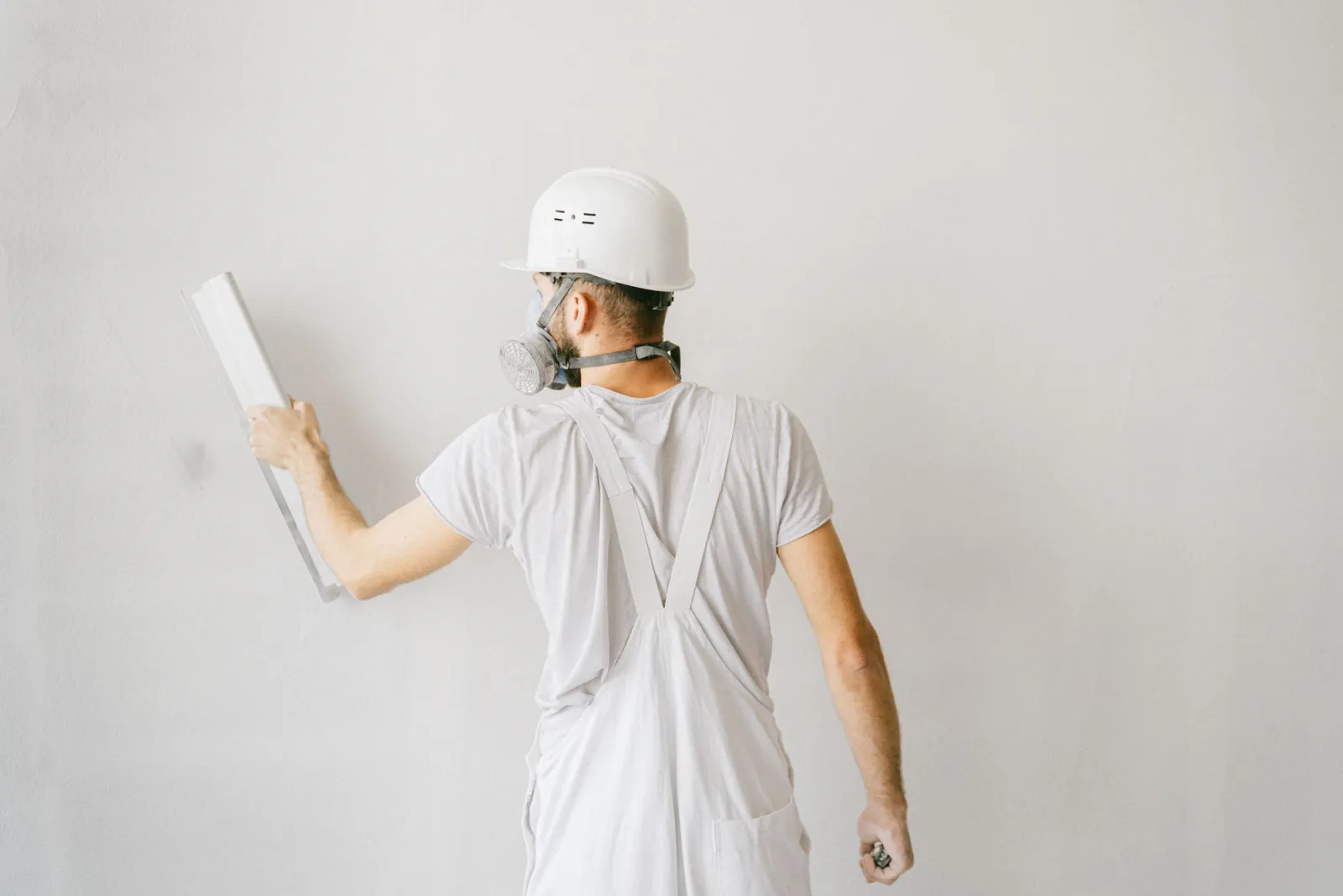 Broad blade drawing a skim coat across an open wall, the step that separates a Level 5 finish from a Level 4