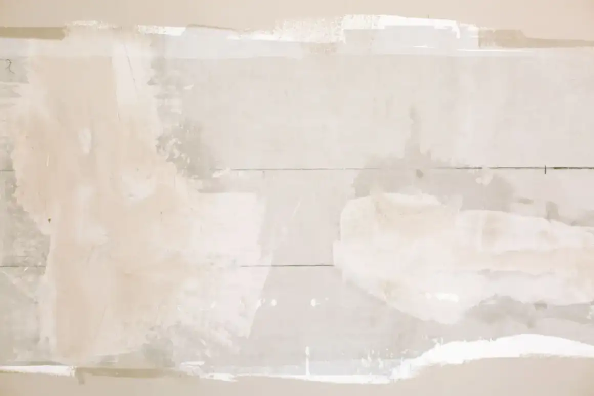Unfinished drywall patch with compound built up over a repaired section before sanding