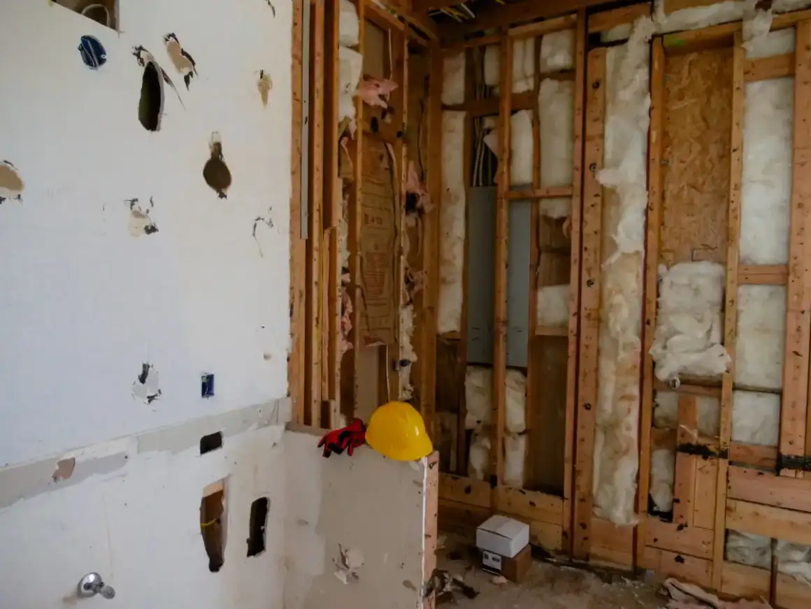 Damaged drywall partly removed, exposing stud framing and insulation during a Madison replacement