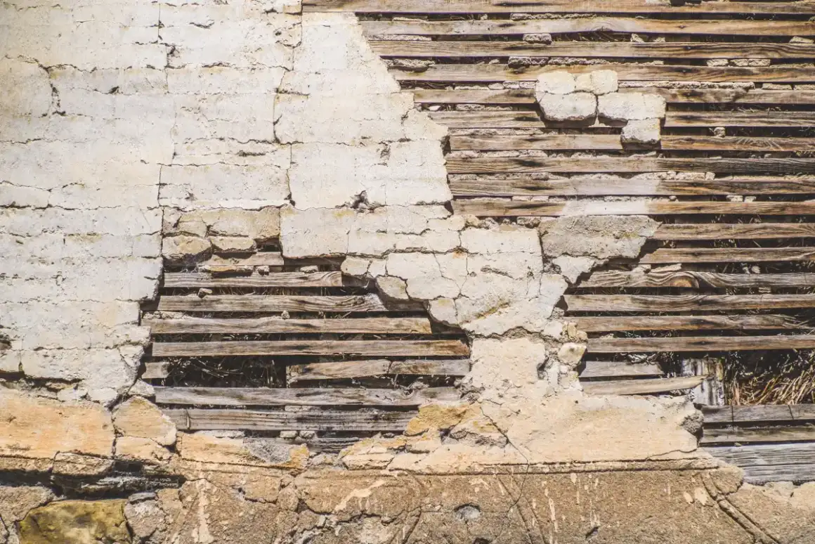 Wood lath exposed behind failed plaster, showing the strips the original keys formed through