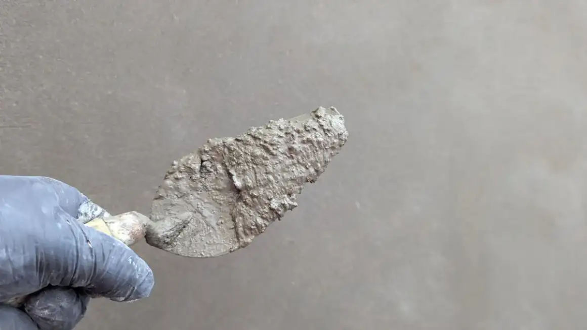 Trowel drawing finish plaster smooth across a repaired wall area